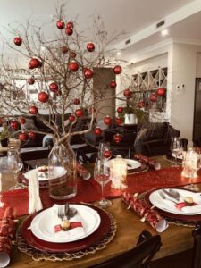 Detalhes na decoração da mesa da ceia de natal com árvore de galhos e bolas vermelhas 